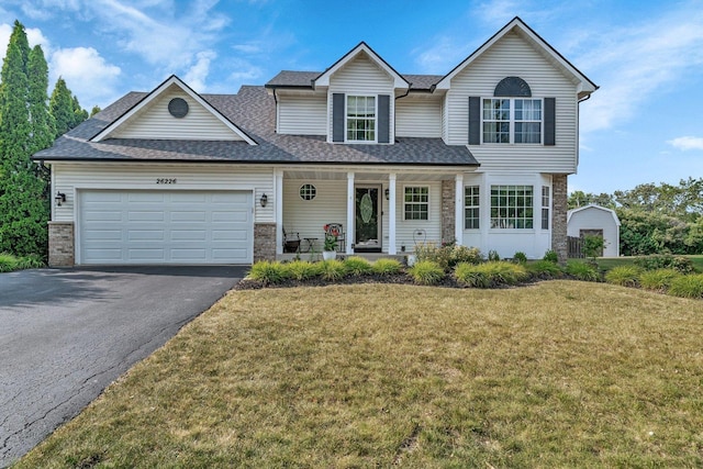 26226 W Tallgrass Trl, Channahon, IL 60410 - view of front of home featuring driveway, covered porch, a front lawn, an attached garage, and roof with shingles