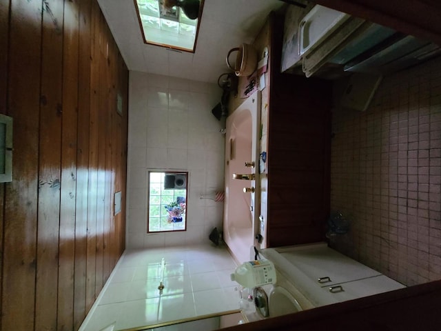 corridor featuring wood walls, a skylight, and tile patterned flooring