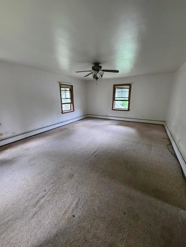 carpeted empty room featuring a ceiling fan and baseboards
