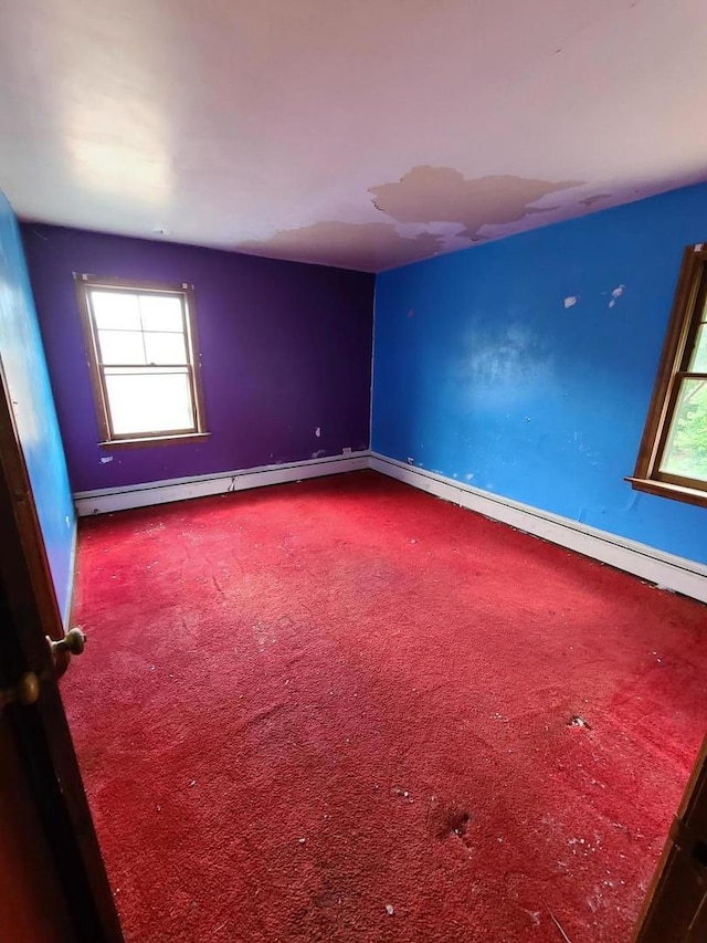 carpeted empty room featuring healthy amount of natural light and a baseboard heating unit