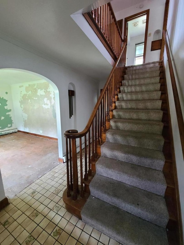 stairs featuring arched walkways, tile patterned flooring, and crown molding