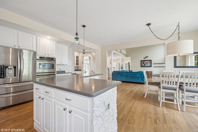 1755 Goldsboro Ln, Crystal Lake, IL 60014 - kitchen featuring appliances with stainless steel finishes, light wood-type flooring, a center island, dark countertops, and pendant lighting