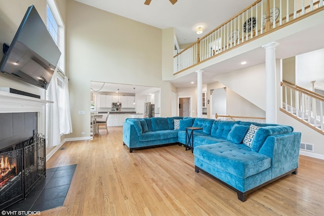 1755 Goldsboro Ln, Crystal Lake, IL 60014 - living room with a high ceiling, light wood-style floors, a tiled fireplace, ceiling fan, and stairway