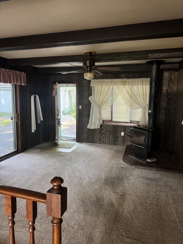 6006 Pershing Ave, Downers Grove, IL 60516 - unfurnished living room with carpet flooring, plenty of natural light, beam ceiling, a wood stove, and wooden walls