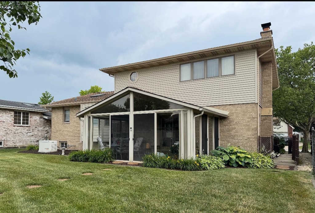 17081 Bonnie Trl W, Oak Forest, IL 60452 - rear view of house with a chimney, a sunroom, a lawn, and brick siding