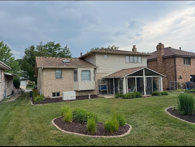 17081 Bonnie Trl W, Oak Forest, IL 60452 - rear view of house featuring a yard, a sunroom, a chimney, and brick siding