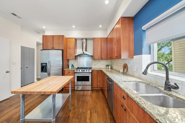 2031 W Saint Paul Ave Unit 2W, Chicago, IL 60647 - kitchen featuring wall chimney range hood, stainless steel appliances, brown cabinetry, light stone counters, and ornamental molding