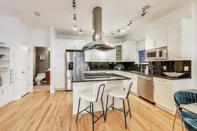2145 W Crystal St Unit 1, Chicago, IL 60622 - kitchen with appliances with stainless steel finishes, island range hood, backsplash, a kitchen island, and light wood-type flooring