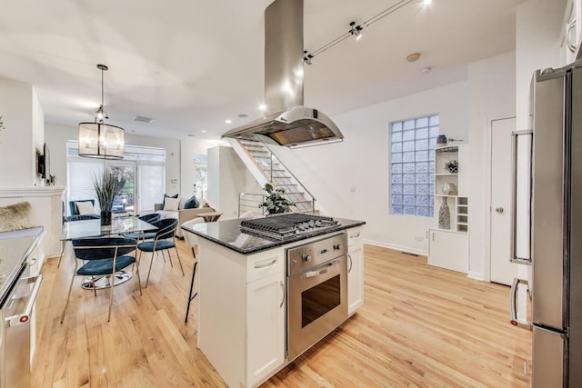 2145 W Crystal St Unit 1, Chicago, IL 60622 - kitchen featuring stainless steel appliances, island range hood, white cabinets, light wood-style floors, and hanging light fixtures