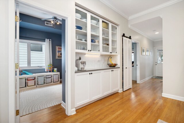 3316 N Leavitt St Unit 2, Chicago, IL 60618 - bar area with a barn door, light wood-style flooring, crown molding, decorative backsplash, and recessed lighting
