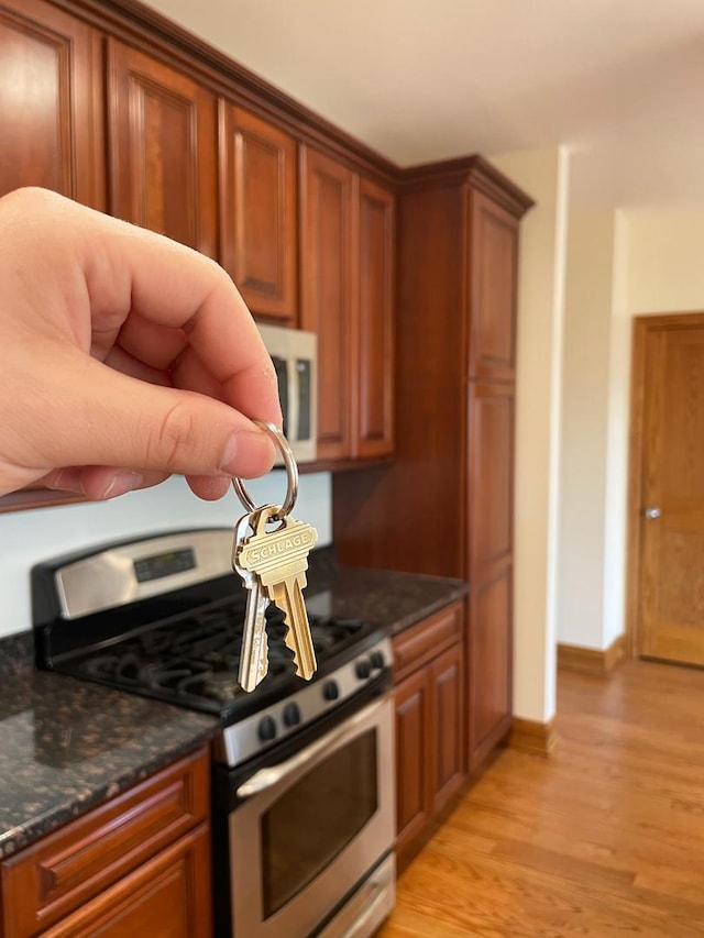 5064 W Agatite Ave Unit 3, Chicago, IL 60630 - kitchen featuring stainless steel range with gas stovetop, white microwave, brown cabinetry, and light wood-style floors