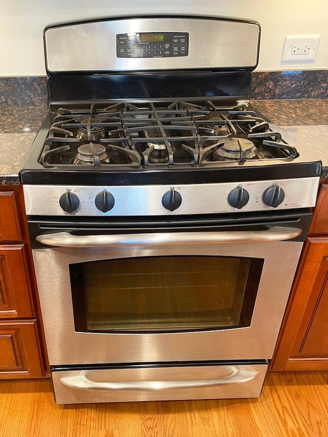 5064 W Agatite Ave Unit 3, Chicago, IL 60630 - kitchen view of stainless steel range with gas cooktop, brown cabinetry, and light wood finished floors