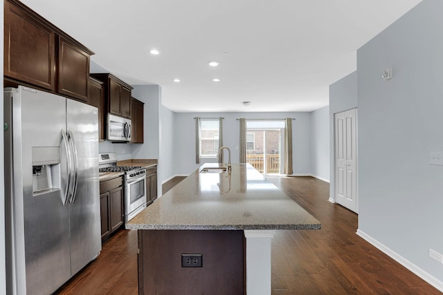 406 Prairie Ct, Morton Grove, IL 60053 - kitchen featuring appliances with stainless steel finishes, dark brown cabinetry, an island with sink, dark wood-style flooring, and light stone counters