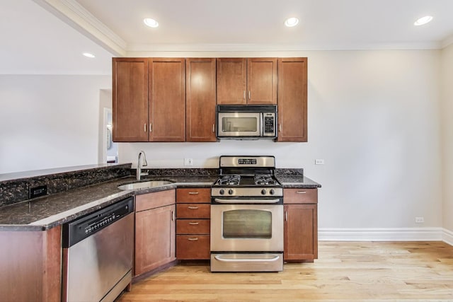 3851 N Kedvale Ave Unit E3, Chicago, IL 60641 - kitchen featuring stainless steel appliances, dark stone countertops, light wood-style flooring, ornamental molding, and recessed lighting