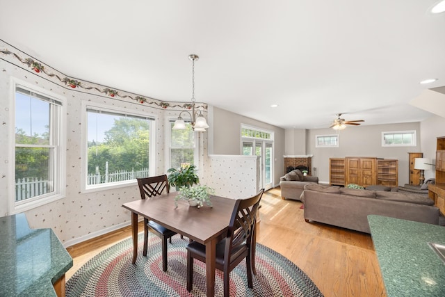 401 Greenwood Rd, Glenview, IL 60025 - dining space featuring light wood-style flooring, a brick fireplace, a ceiling fan, plenty of natural light, and wallpapered walls