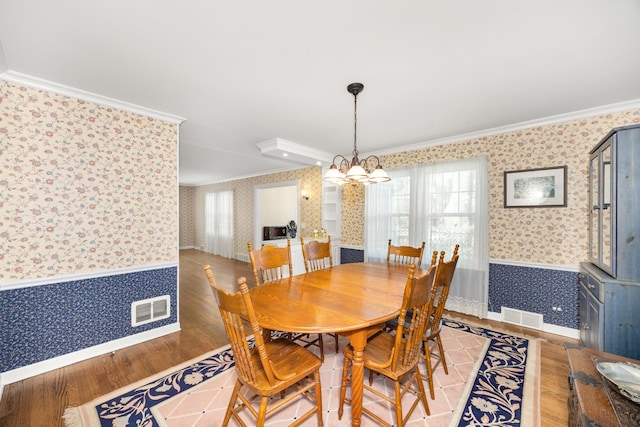401 Greenwood Rd, Glenview, IL 60025 - dining area featuring wallpapered walls, crown molding, a wainscoted wall, light wood-type flooring, and a chandelier