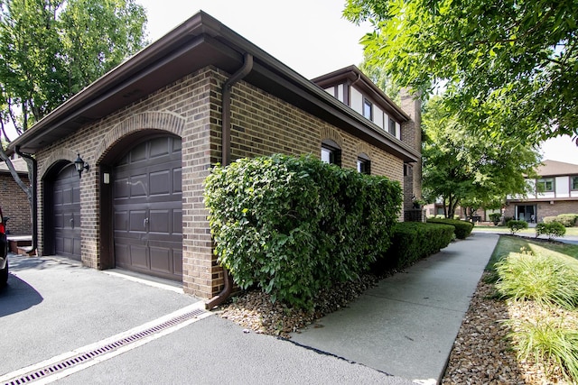 12256 S Arbor Trl Unit 11W, Palos Heights, IL 60463 - view of home's exterior featuring brick siding, asphalt driveway, and a garage
