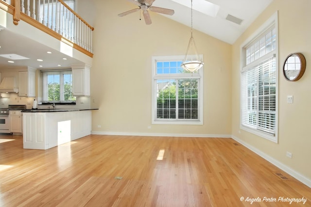 32756 N Stone Manor Dr, Grayslake, IL 60030 - unfurnished living room with high vaulted ceiling, light wood-style flooring, ceiling fan, and a skylight
