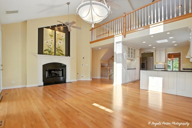 32756 N Stone Manor Dr, Grayslake, IL 60030 - unfurnished living room with ceiling fan, a fireplace with flush hearth, light wood finished floors, and a high ceiling