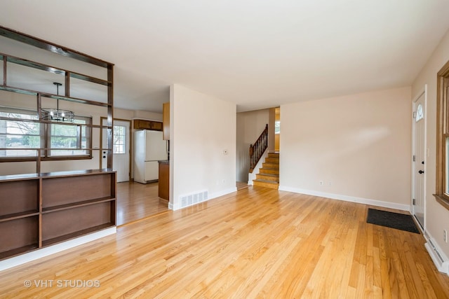 401 Elden Dr, Cary, IL 60013 - unfurnished living room featuring wood finished floors, stairs, and a chandelier