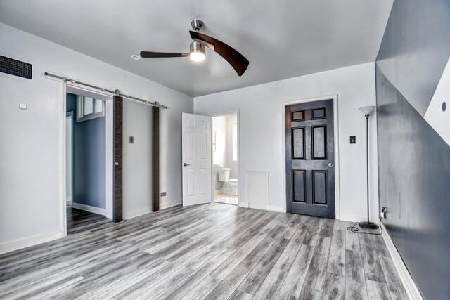 2425 Flossmoor Rd, Flossmoor, IL 60422 - unfurnished bedroom with a barn door, wood finished floors, connected bathroom, and ceiling fan