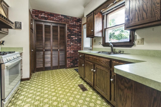 3536 Buck Ave, Joliet, IL 60431 - kitchen featuring white range with gas stovetop, light countertops, dark brown cabinetry, light flooring, and brick wall