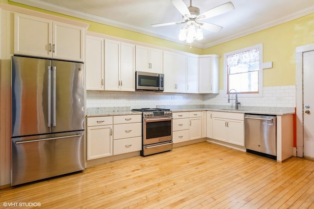 2721 W Prindiville St, Chicago, IL 60647 - kitchen featuring appliances with stainless steel finishes, backsplash, light wood finished floors, white cabinets, and ornamental molding