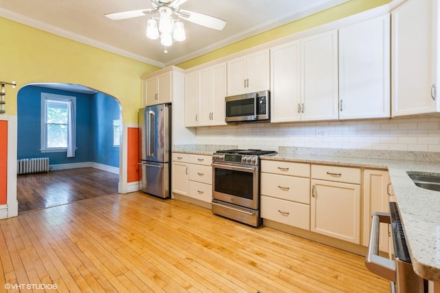 2721 W Prindiville St, Chicago, IL 60647 - kitchen with appliances with stainless steel finishes, radiator heating unit, light wood-type flooring, tasteful backsplash, and ornamental molding