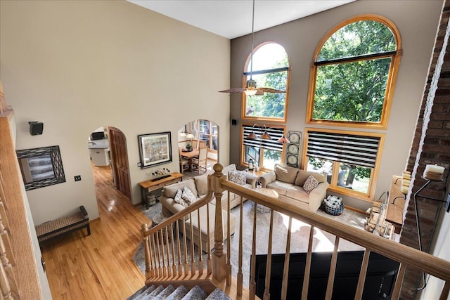 531 Danbury Dr, Oswego, IL 60543 - living area featuring arched walkways, wood finished floors, ceiling fan, a towering ceiling, and stairway