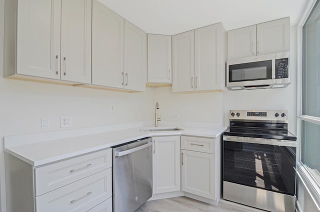 405 N Wabash Ave Unit 506, Chicago, IL 60611 - kitchen featuring appliances with stainless steel finishes, light countertops, light wood-style floors, and white cabinets