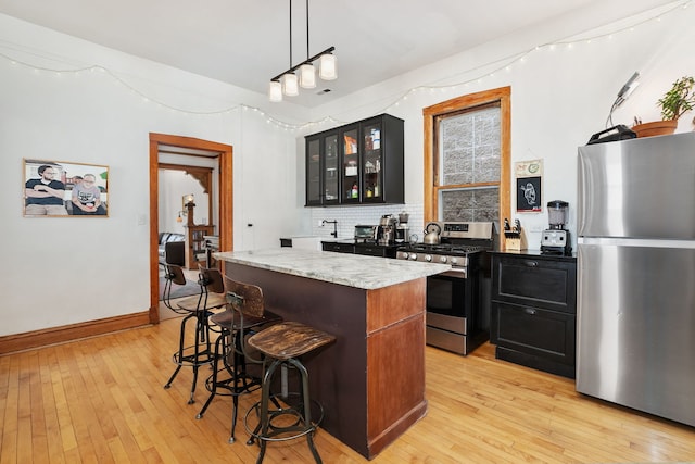 1630 S Fairfield Ave, Chicago, IL 60608 - kitchen with appliances with stainless steel finishes, dark cabinetry, a kitchen island, and light wood finished floors