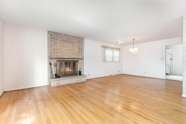 712 Central Park Ave, Flossmoor, IL 60422 - unfurnished living room with a chandelier, wood finished floors, and a brick fireplace