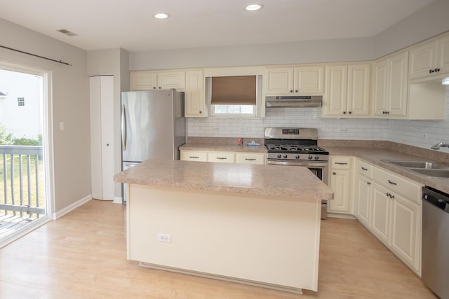 16409 Teton Dr Unit D, Lockport, IL 60441 - kitchen featuring stainless steel appliances, under cabinet range hood, a kitchen island, backsplash, and light wood finished floors