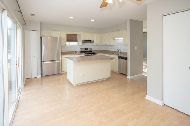 16409 Teton Dr Unit D, Lockport, IL 60441 - kitchen with appliances with stainless steel finishes, under cabinet range hood, tasteful backsplash, a kitchen island, and light wood finished floors