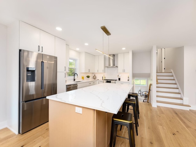 5028 Coyle Ave, Skokie, IL 60077 - kitchen with appliances with stainless steel finishes, wall chimney exhaust hood, light wood-style flooring, a breakfast bar area, and recessed lighting