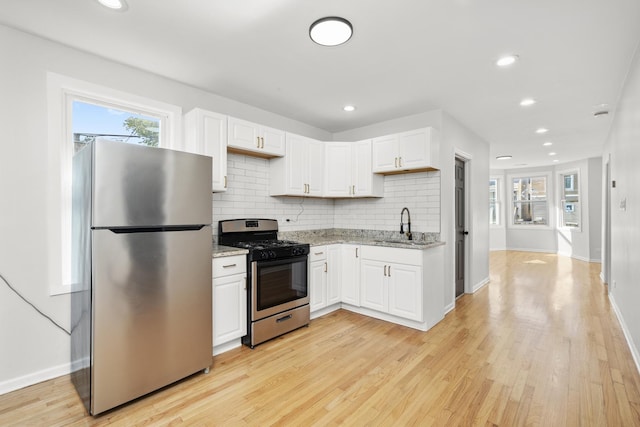 712 W 48th Pl, Chicago, IL 60609 - kitchen featuring appliances with stainless steel finishes, white cabinets, tasteful backsplash, light stone counters, and light wood-style floors