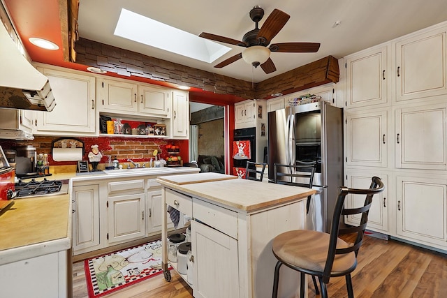13420 Florence Rd, Mokena, IL 60448 - kitchen with exhaust hood, appliances with stainless steel finishes, ceiling fan, light wood-style flooring, and a center island