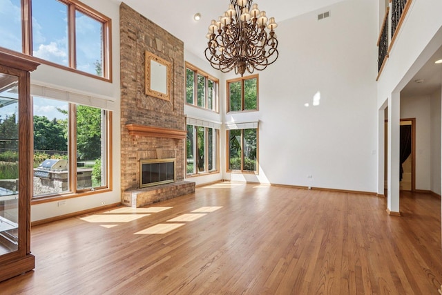 641 Mason Ln, Lake In The Hills, IL 60156 - unfurnished living room with a high ceiling, wood finished floors, a brick fireplace, and a chandelier