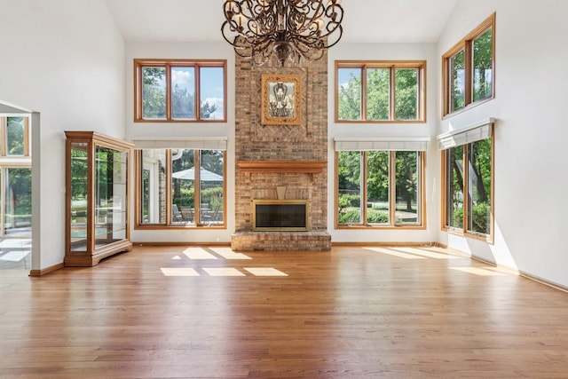 641 Mason Ln, Lake In The Hills, IL 60156 - unfurnished living room featuring high vaulted ceiling, a chandelier, a fireplace, and wood finished floors