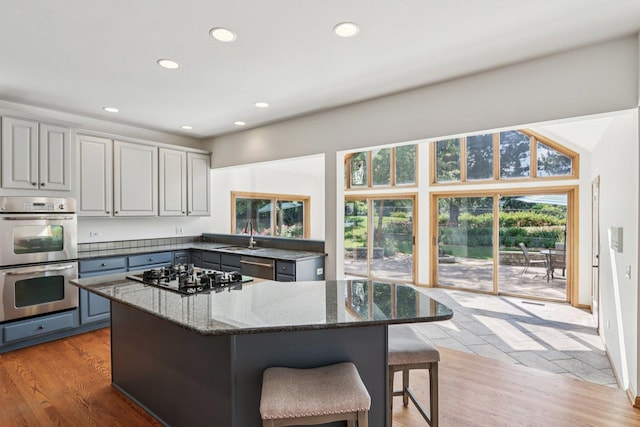 641 Mason Ln, Lake In The Hills, IL 60156 - kitchen featuring appliances with stainless steel finishes, gray cabinets, a breakfast bar area, dark stone countertops, and recessed lighting