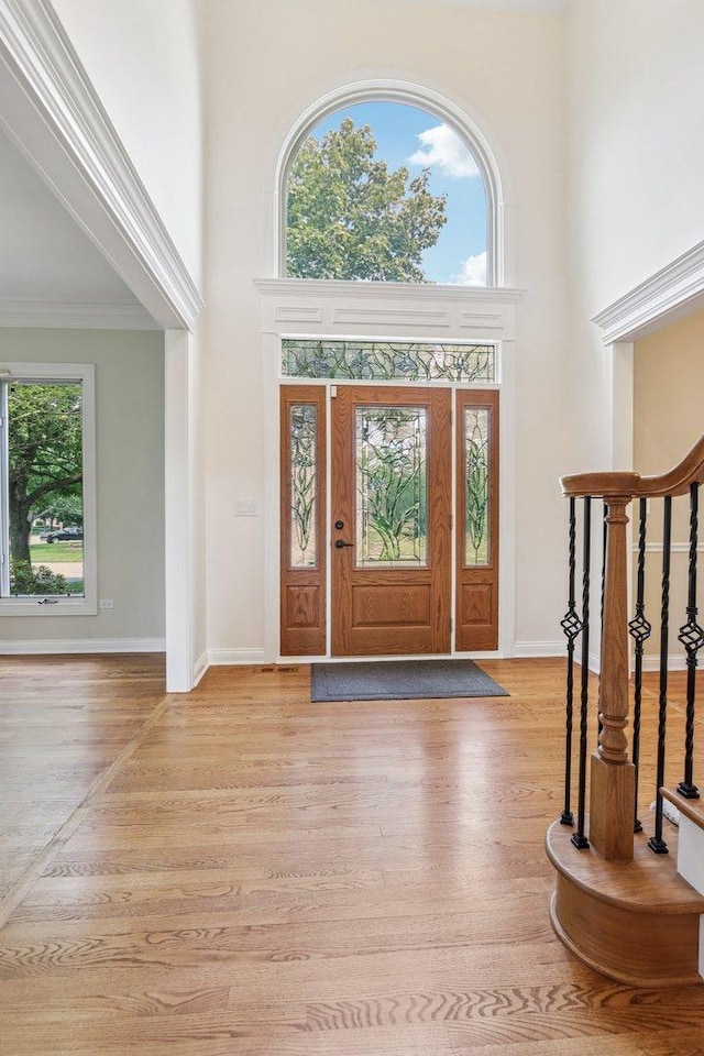 641 Mason Ln, Lake In The Hills, IL 60156 - foyer entrance with a towering ceiling, light wood-style floors, stairs, and crown molding