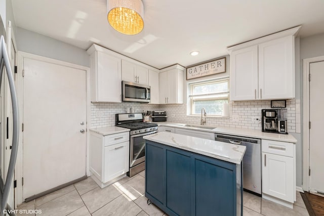 247 Tioga Ave, Bensenville, IL 60106 - kitchen with appliances with stainless steel finishes, tasteful backsplash, white cabinetry, a center island, and light stone countertops