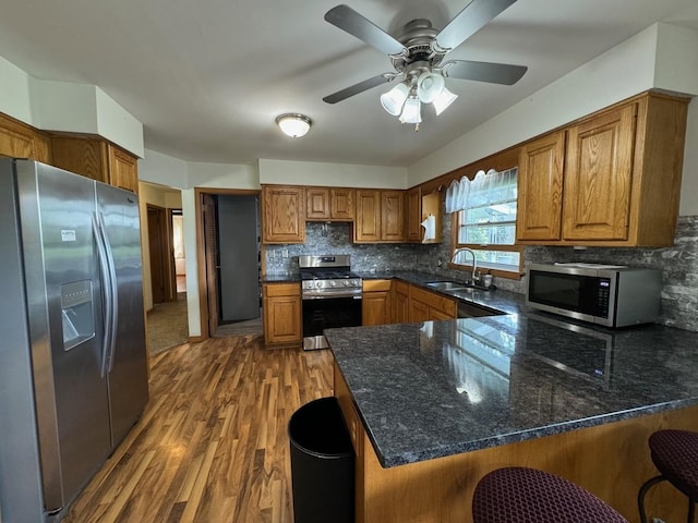 1536 Marberly Dr, Rockford, IL 61103 - kitchen with appliances with stainless steel finishes, a peninsula, brown cabinets, and wood finished floors