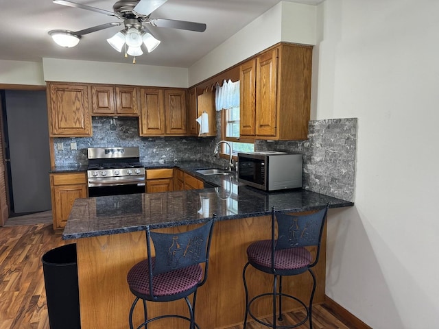 1536 Marberly Dr, Rockford, IL 61103 - kitchen with appliances with stainless steel finishes, brown cabinetry, dark stone countertops, and a peninsula