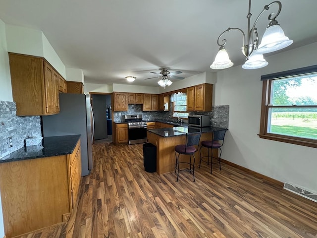 1536 Marberly Dr, Rockford, IL 61103 - kitchen with stainless steel appliances, a peninsula, brown cabinetry, a ceiling fan, and backsplash