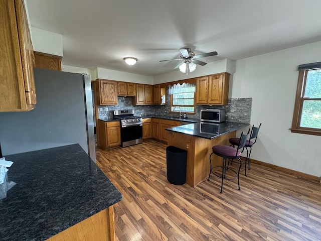 1536 Marberly Dr, Rockford, IL 61103 - kitchen featuring appliances with stainless steel finishes, a peninsula, brown cabinets, and healthy amount of natural light