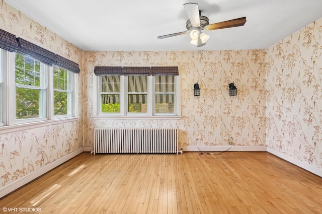 3900 N Keeler Ave, Chicago, IL 60641 - unfurnished room with radiator heating unit, light wood-style flooring, wallpapered walls, and a ceiling fan