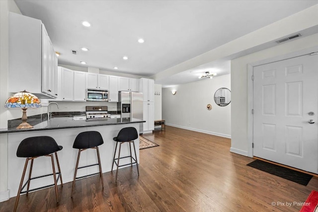 1124 W Diversey Pkwy Unit 2W, Chicago, IL 60614 - kitchen featuring stainless steel appliances, a peninsula, dark countertops, white cabinetry, and recessed lighting