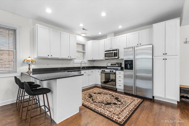 1124 W Diversey Pkwy Unit 2W, Chicago, IL 60614 - kitchen featuring stainless steel appliances, a peninsula, white cabinets, dark countertops, and recessed lighting