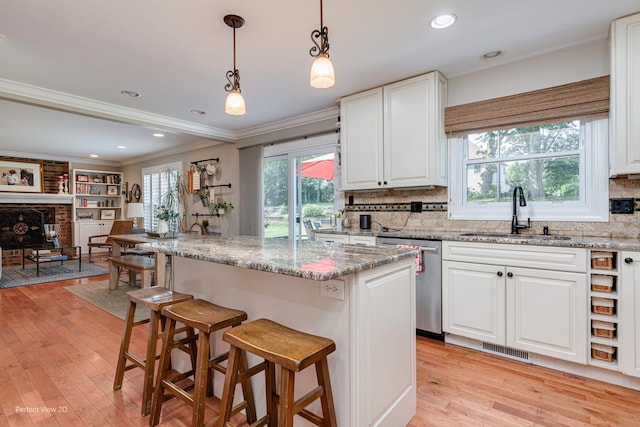985 W Bauer Rd, Naperville, IL 60563 - kitchen with stainless steel dishwasher, light wood finished floors, a kitchen bar, white cabinetry, and ornamental molding